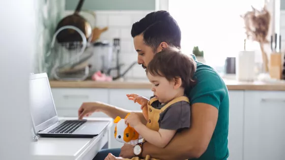 Father on a laptop with baby boy sitting on his lap