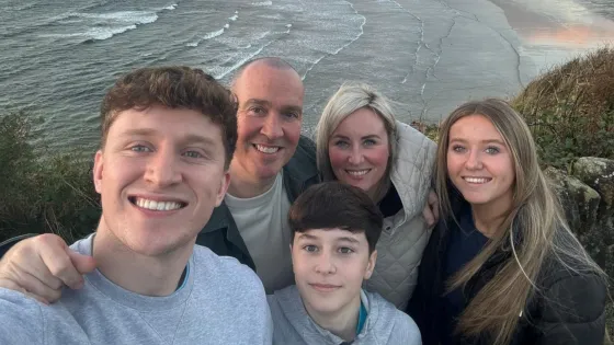 A family smiles together on a beach.