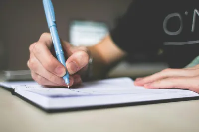 A pen touches a pad of paper as someone writes down their thoughts.
