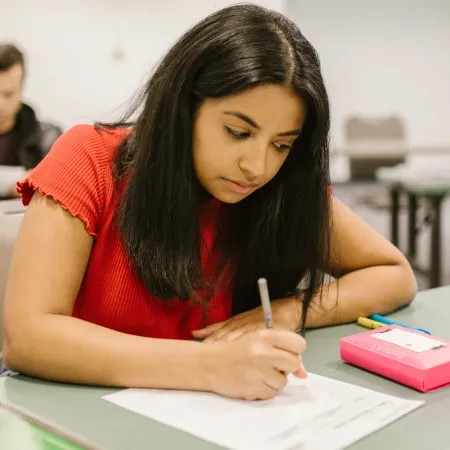 Young girl writing on an exam paper in an exam hall