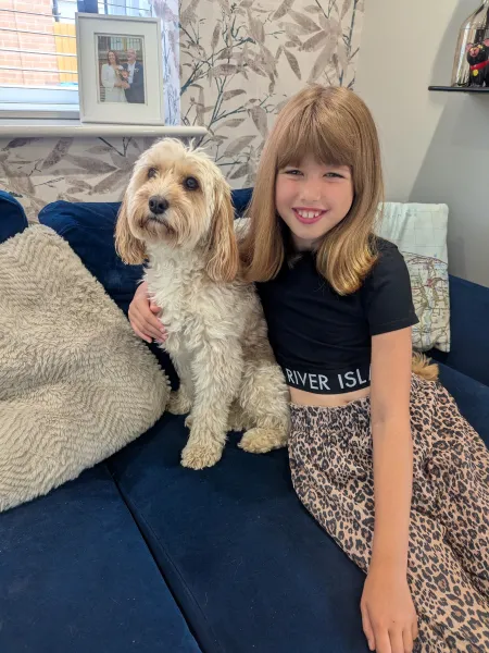 A girl cuddles a dog on a sofa.